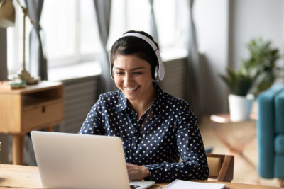 a high school girl student wearing headphone smiling look at laptop at home